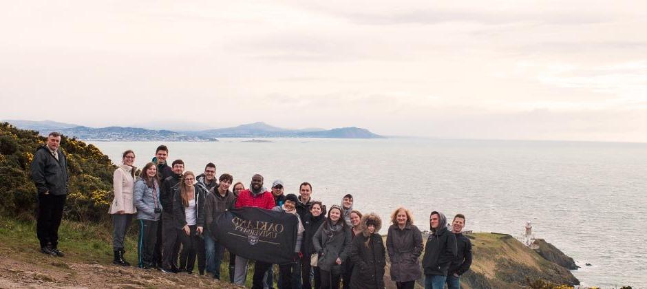 一群在欧大留学的学生举着欧大旗帜站在大海前
