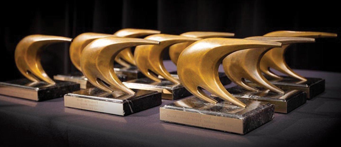 gold sail shaped awards lined up on a table
