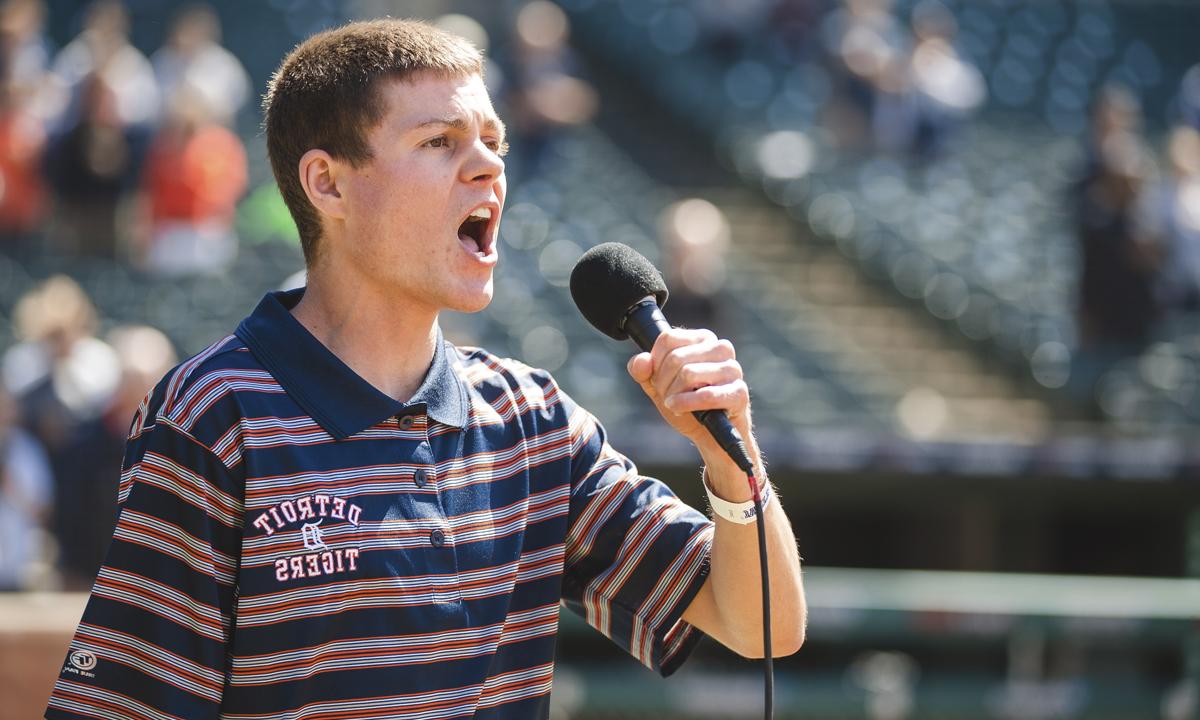 Photo of a young man singing into a microphone at comerica park