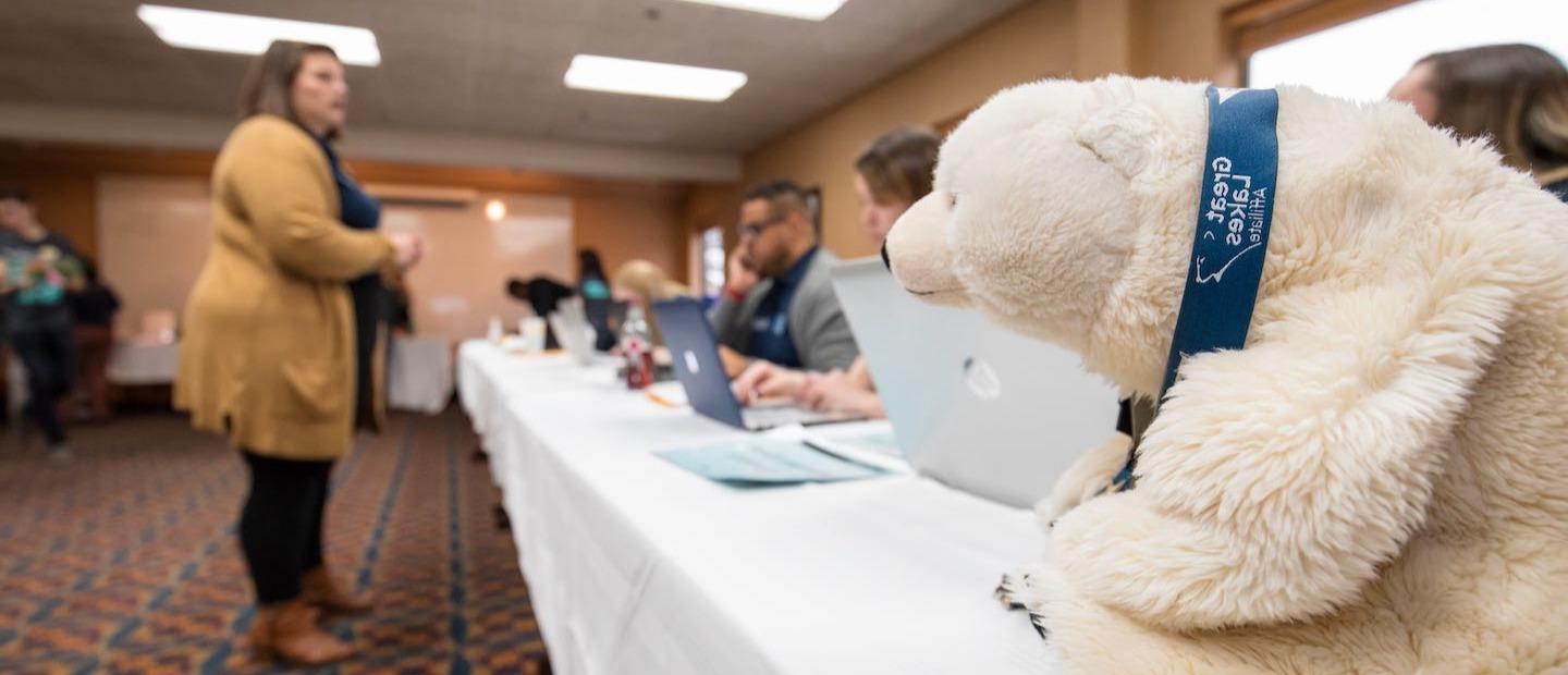 北极熊毛绒玩具在长桌与学生用电脑交谈的照片