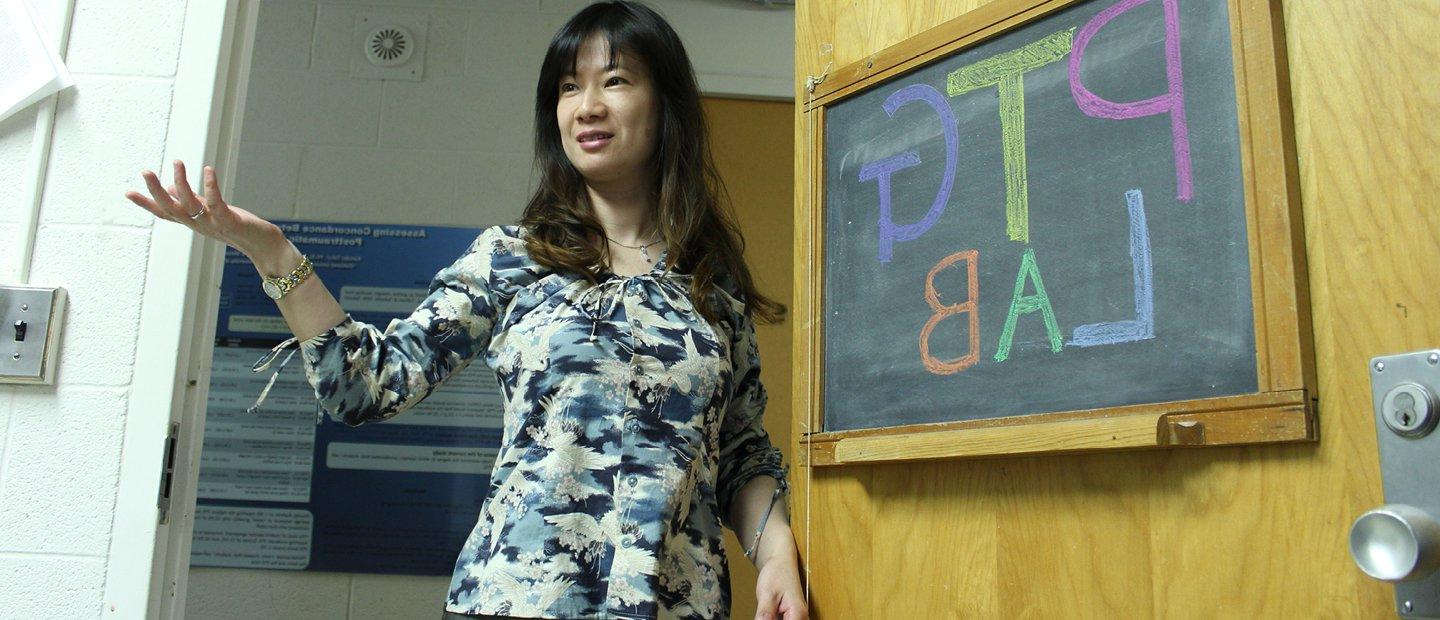 一位教授站在黑板前，黑板上写着“P T G实验室”.