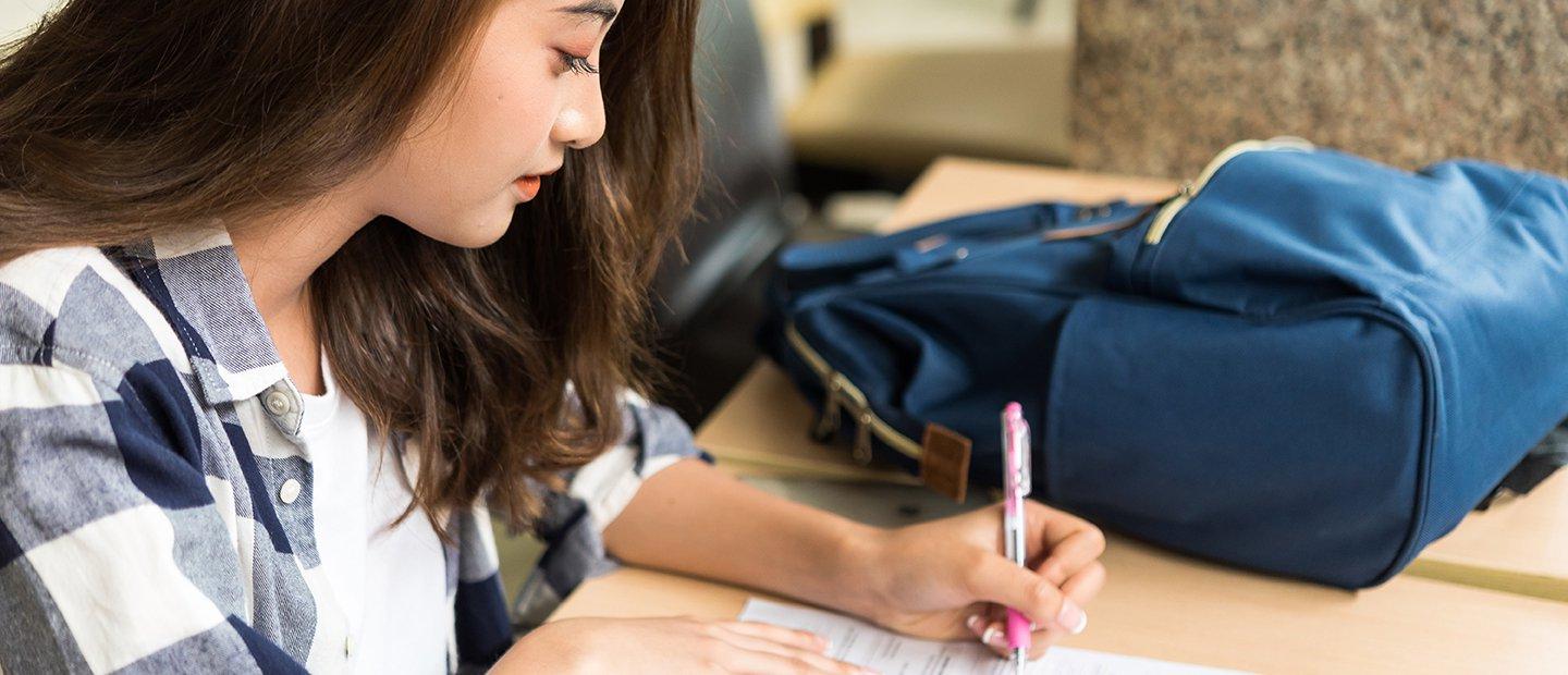 一个女学生坐在桌子前，正在填写表格.